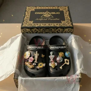 Black OneRepublic Crocs with artistic charms inside an open black and gold box on a light wooden surface!