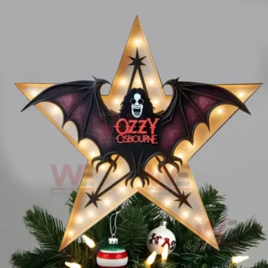 A glowing star shaped Ozzy Osbourne Christmas tree topper with black bat wings and red lettering placed above a decorated Christmas tree.