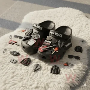 Black Papa Roach Crocs with scattered rock themed charms displayed on a soft white rug!