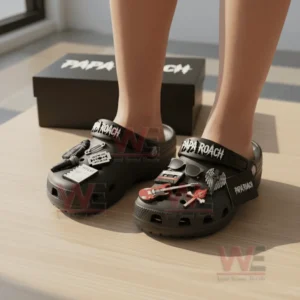 Person wearing black Papa Roach Crocs with music and rock style charms on a wooden floor!