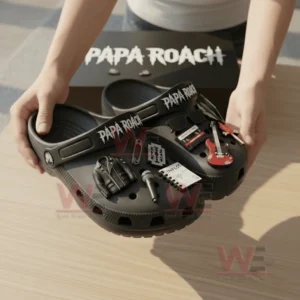 Hands holding black Papa Roach Crocs with rock inspired charms above a black branded box!