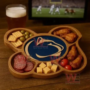A wooden platter with a Penn State design surrounded by assorted snacks sits near a glass of beer with a sports game on a television!