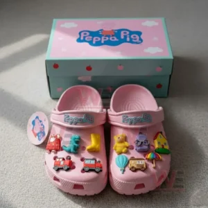 Pink Peppa Pig clogs with multiple colorful charms displayed in front of a themed box.