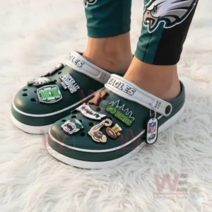 Green Eagles clogs with multiple themed charms worn on a white furry surface!