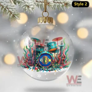 A clear globe ornament featuring a vivid drum set decorated with holiday lights and colorful designs resting in snow!