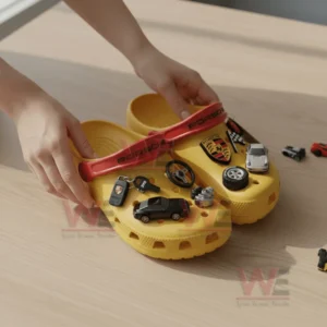 Yellow clogs decorated with car themed charms placed on a wooden table.