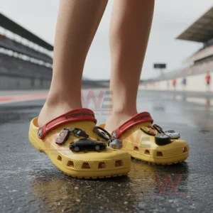 Yellow clogs with car themed charms worn on a racetrack.