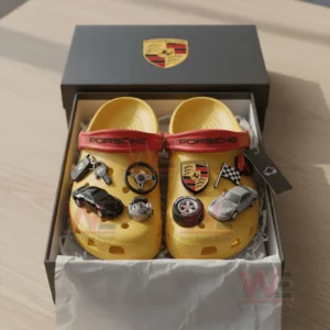 Yellow clogs with car themed charms arranged inside an open box.