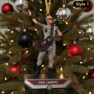 A guitar player ornament raising one arm while standing on a decorated platform before a Christmas tree.