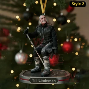 A seated singer ornament holding a microphone on a suspended platform before a Christmas tree.