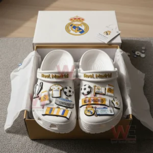 White Real Madrid themed clogs placed inside an open box with multiple football related charms attached to the shoes.