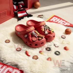 Red clogs with Red Hot Chili Peppers decorations rest on a white rug next to small band-themed items.