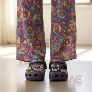 Person wearing patterned pants and purple Ringo Starr clogs with decorative charms indoors.