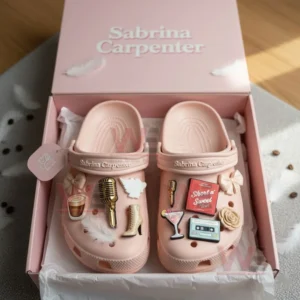 Pink Sabrina Carpenter clogs in a box decorated with multiple themed charms!