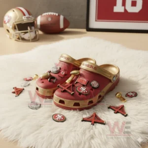 San Francisco 49ers red and gold Crocs with football themed charms displayed beside helmet and football on white rug!