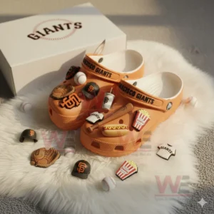 Orange San Francisco Giants Crocs with baseball themed charms displayed on a white fluffy mat next to their branded box!