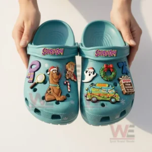 Scooby Doo Mystey Machine Crocs Clogs with Charms 7 Hands holding blue Scooby Doo clogs with colorful character and holiday decorations on a plain background.