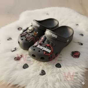 Gray clogs with Scorpions decorations featuring skull and rock motifs placed on a white fur rug with scattered charms.
