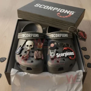 Gray Scorpions clogs with rock-style decorations placed inside an open box on a wooden table.