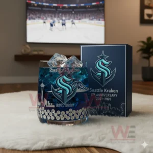 A Seattle Kraken glass and box positioned on a white rug with a hockey game showing on a television behind them!