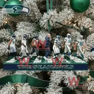 Alt text: A Seattle Seahawks ornament featuring players and coach, hanging on a Christmas tree with green ribbon and team logos.