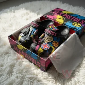 Black clogs with Sex Pistols decorations resting in a vivid punk-themed gift box.