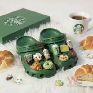 Green Starbucks Crocs with coffee and pastry themed charms displayed beside bread and coffee cup on white furry rug!