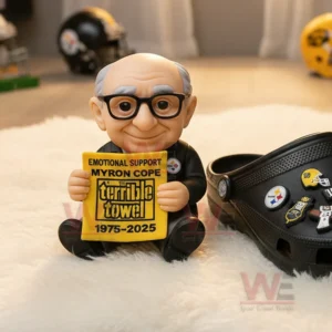 Elderly toy figure with glasses holding a commemorative towel beside a black themed shoe.