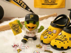 Green baseball mascot toy holding a fiftieth anniversary towel beside yellow decorated shoes.