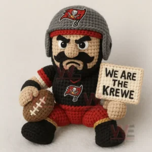 Crocheted pirate themed football figure in black red and gray holding a brown football and a stitched sign while seated.