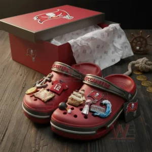 Red Buccaneers Crocs with themed charms displayed beside matching team box on wooden surface!