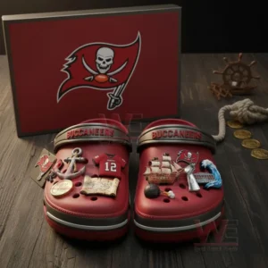 Red Tampa Bay Buccaneers Crocs with pirate and football themed charms placed in front of team box on wooden background!