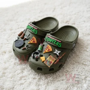 Olive green Teenage Mutant Ninja Turtles themed Crocs with multiple detailed charms including pizza slices, ninja weapons, and TMNT logo.