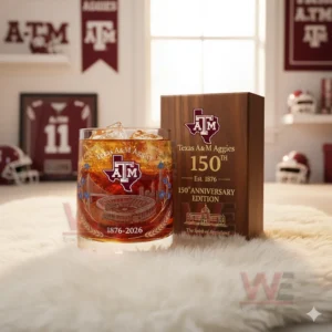 A Texas AM themed drink glass with ice next to a wooden anniversary box in a burgundy sports decorated room!