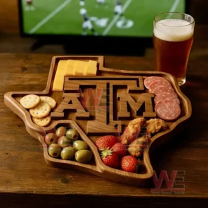 A state shaped wooden tray filled with assorted snacks sits on a wooden table next to a glass of beer with a sports screen in the background!
