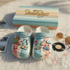Beach Boys themed Crocs with pastel stripes and decorative charms featuring music and surf symbols beside a matching logo box!