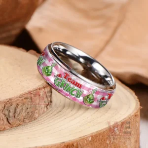 Silver ring on wood showing pink band with repeating Grinch themed graphics!