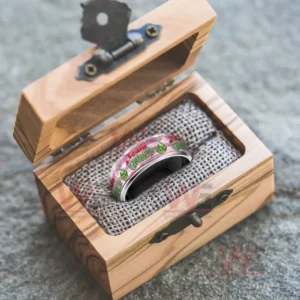 Silver ring with pink Grinch themed band inside an open wooden gift box!