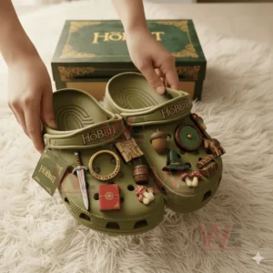 Olive green The Hobbit Crocs with fantasy-themed charms held above a fluffy rug in front of a matching box.