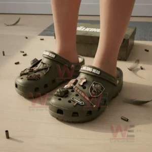 Person wearing olive green The Walking Dead Crocs with detailed zombie and survival themed decorations.
