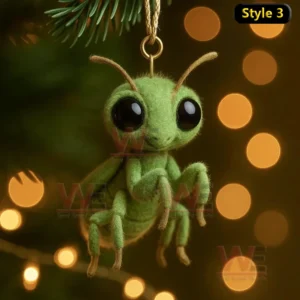 Green fuzzy insect ornament hanging from pine branch with warm lights behind it.