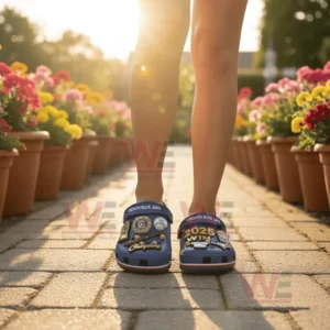 Person wearing blue Toronto Blue Jays Crocs with championship charms in sunlight surrounded by flowers.