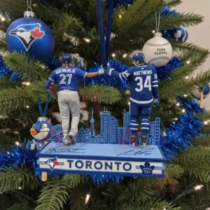 A Christmas tree ornament of two athletes on a Toronto skyline platform hanging among blue decorations.