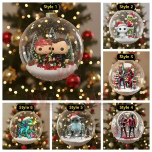 Clear Christmas ornament with two small figures standing in snow among trees and gifts.