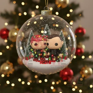 Clear ornament with two small characters standing in a snowy holiday setting.