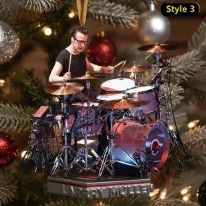 A drummer ornament playing a full drum kit on a platform before a Christmas tree.