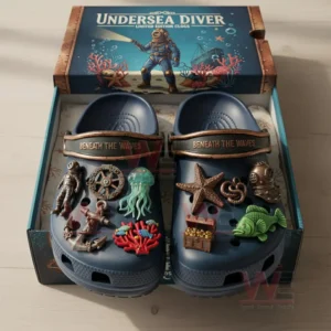 Blue undersea diver themed clogs placed inside an open box with multiple ocean related charms attached to the shoes.