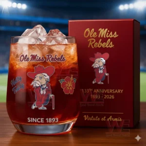 University of Mississippi Rebels 133rd Anniversary Whiskey Glass 3 Alt text: A close-up of a whiskey glass with the Ole Miss Rebels logo and a commemorative anniversary box, set against a football field backdrop.