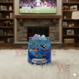 A Utah Mammoth glass filled with ice positioned on a white rug with a fireplace and a sports broadcast visible behind it.