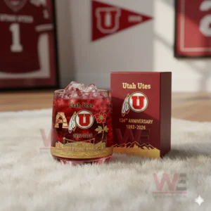 A Utah Utes themed iced drink glass next to a red anniversary box on a fluffy rug in a sports decorated room!
